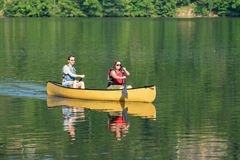 2 people paddling a canoe on a lake